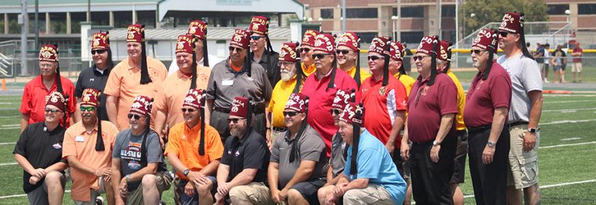 Shriners in traditional fezzes gathered on the field at Tucci Stadium