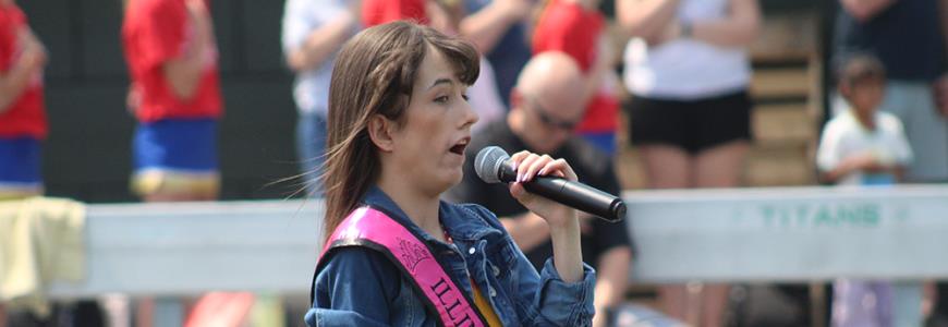 A Shriners patient ambassador sings the anthem before the game